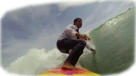 man surfing a wave dressed as an office worker